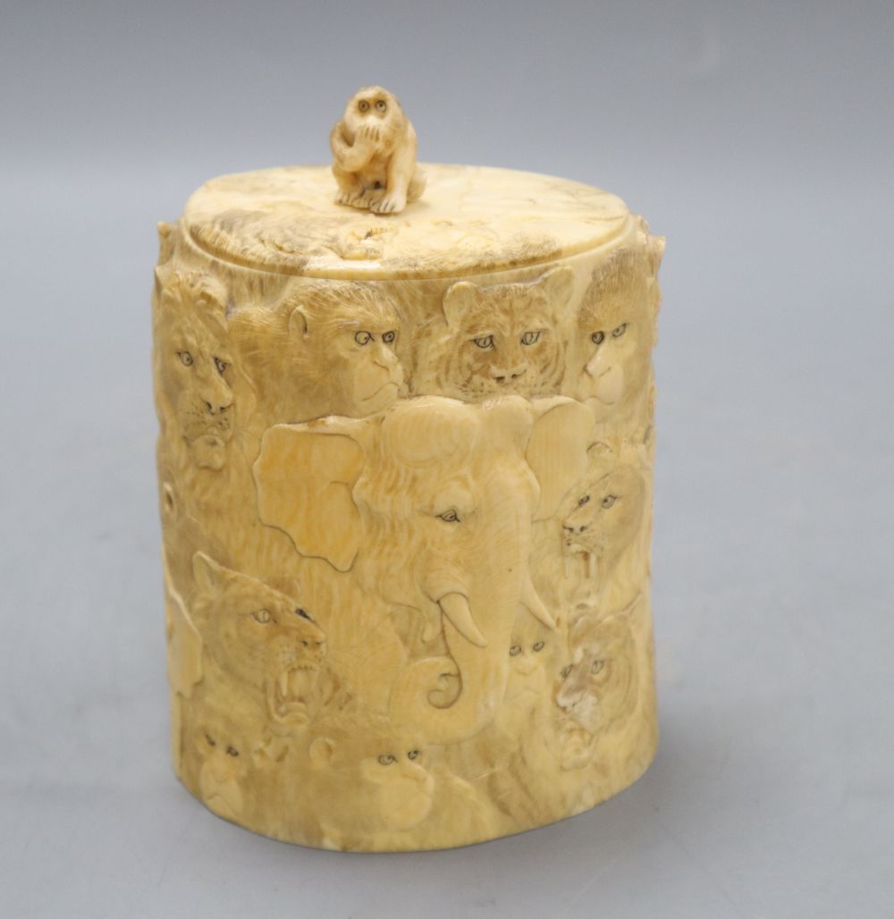A Japanese ivory box and cover, Meiji Period, carved with elephants, lions, monkeys, etc. (lacking base), overall height including lid